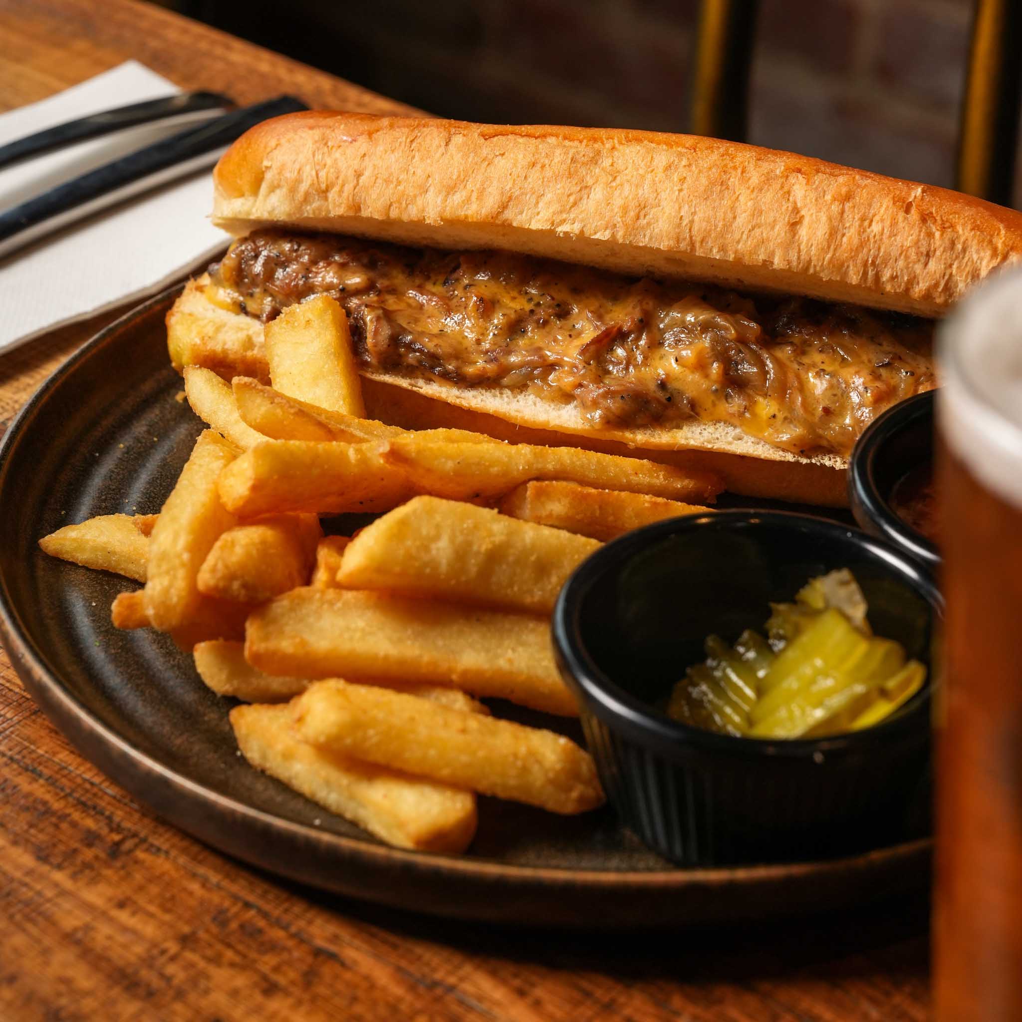 Murrays Hot Brisket Roll | House-Smoked Brisket Piled Into A Toasted Long Roll With Melted Cheese, Caramelised Onion And House BBQ Glaze For Dipping. Served With Chips And Pickles | $26.80