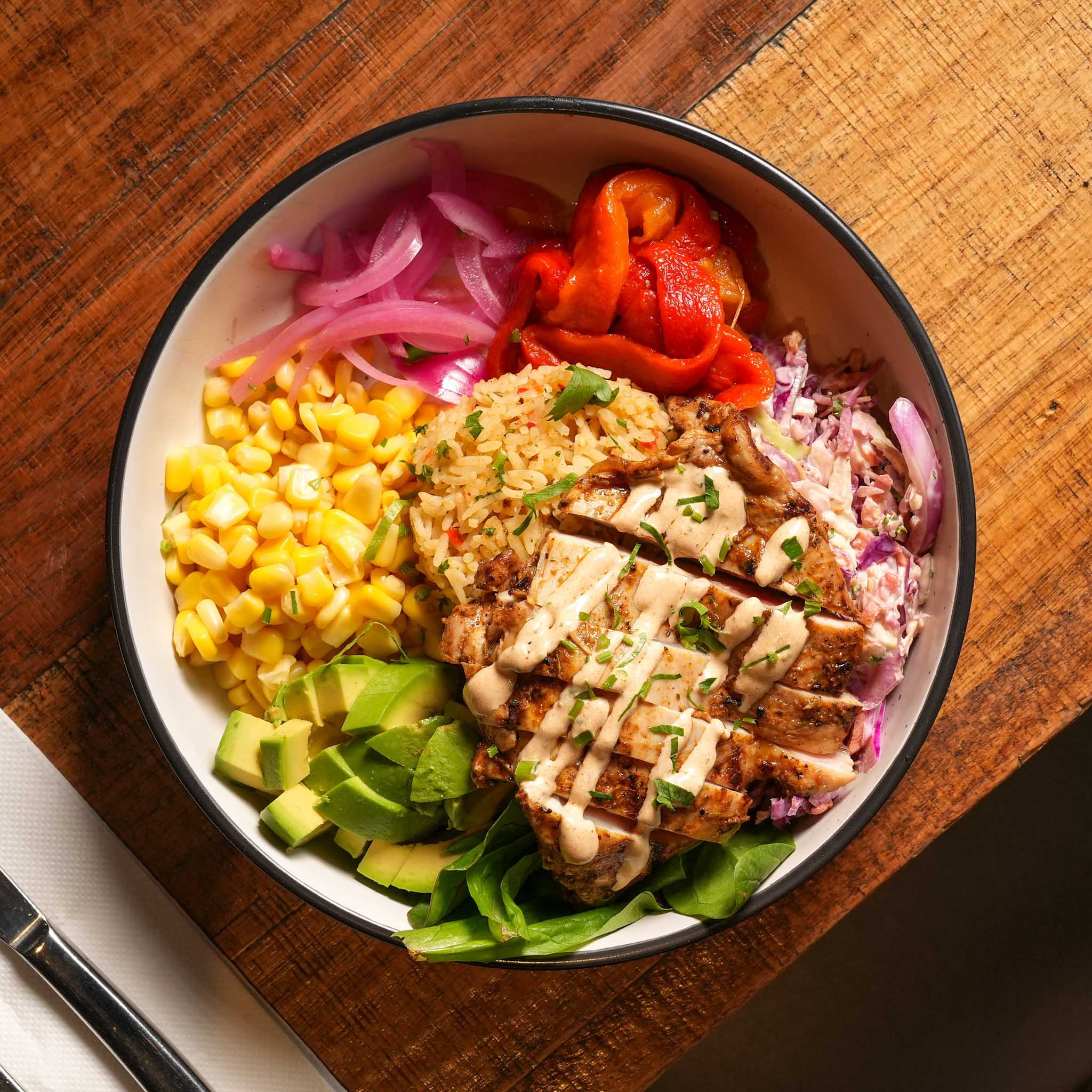Cajun Chicken Protein Bowl | Grilled Cajun Chicken Thigh Served Over Jambalaya Rice And Slaw With Roasted Capsicum, Corn, Spinach, Pickled Onion, Avocado And Chipotle Yoghurt | $28.80