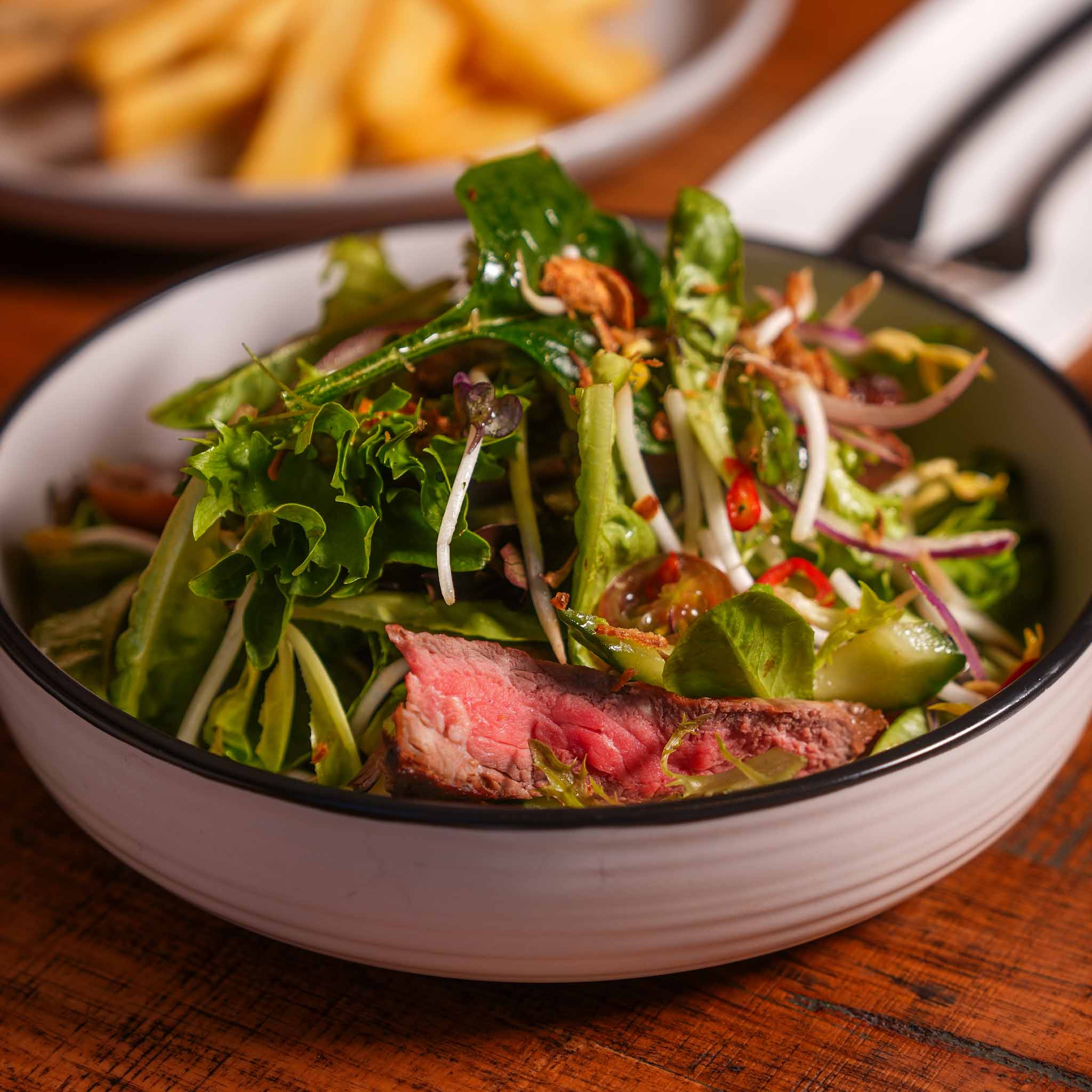 Thai Rump Cap Beef Salad | Char-Grilled Rump Cap Served Over Mesclun With Tomato, Onion, Chilli, Asian Herbs And Peanuts, Finished With A Thai-Style Dressing | $25.80